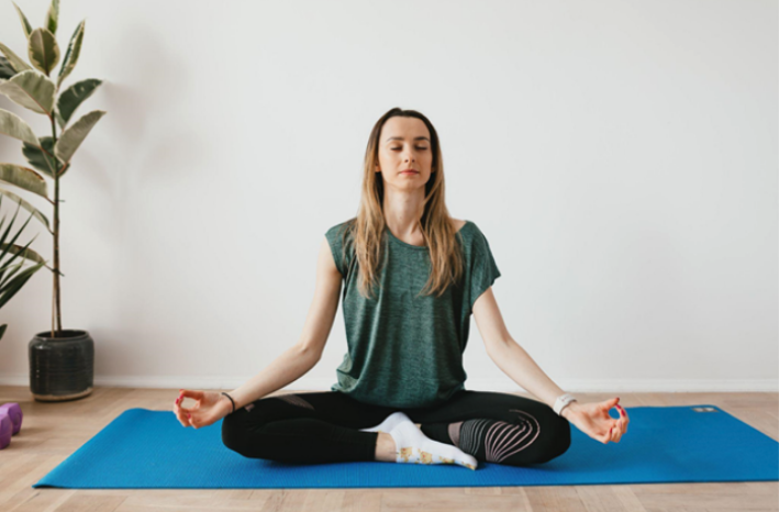 peaceful lady sitting in padmasana pose while meditating on mat