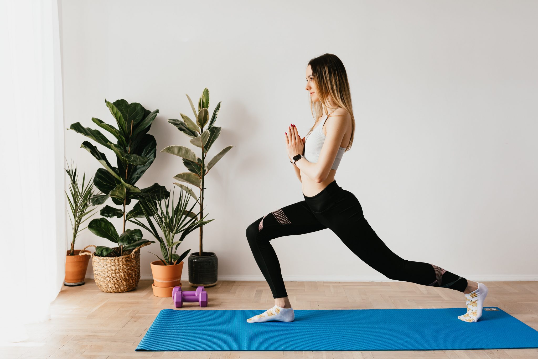 slender woman standing in crescent lunge with prayer hands